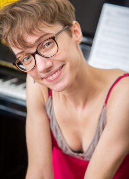 Skinny nerdy girl with short hair displays her unshaved snizz on piano bench